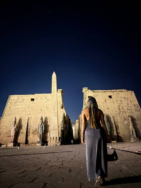 Woman standing in front of an ancient temple at night