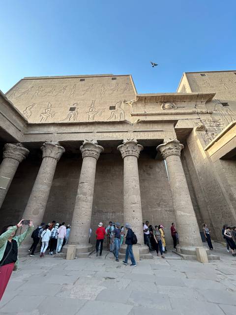 Tourists observing a large temple structure with columns.