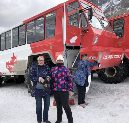 Group of people posing in front of a large vehicle in a snowy landscape.