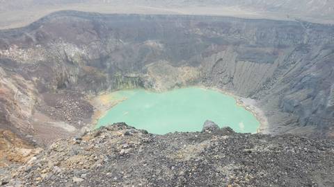 Crater lake with vibrant turquoise water viewed from above.