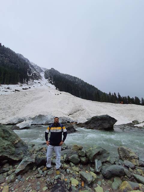 Individual standing beside a river with snowy landscape.