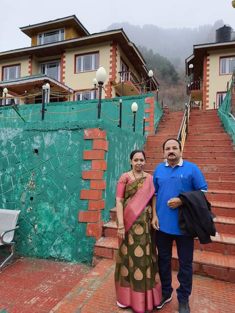 Couple posing in front of a building with mountain view.