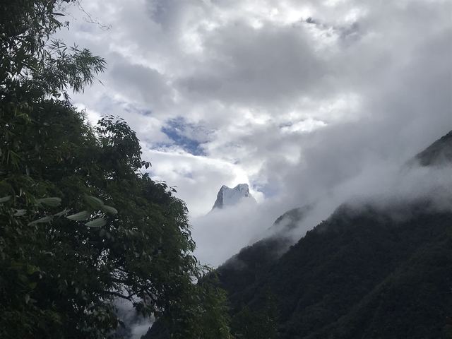 Cloudy mountain peak with surrounding greenery.