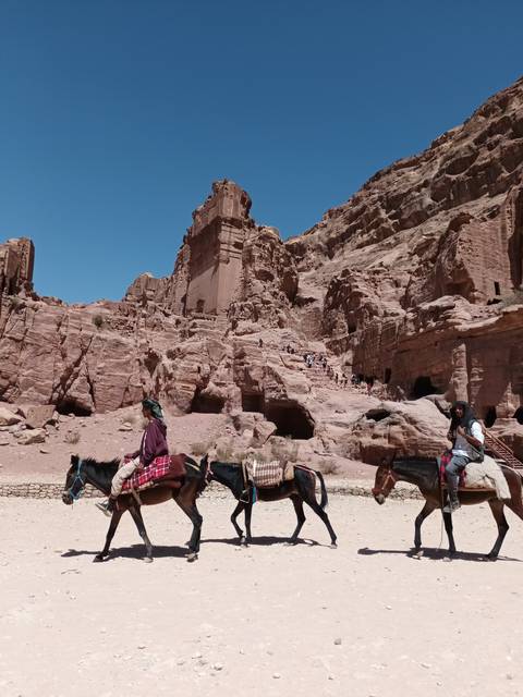       People riding horses through a desert canyon.
  
