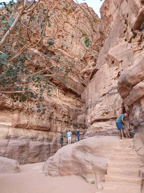 People walking through a narrow rock canyon.