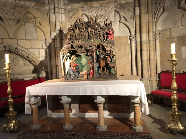       Altar with candles in an ornate stone church.
  