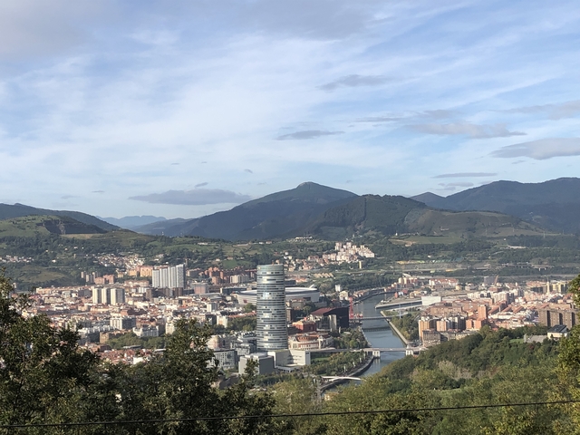       Cityscape with river, bridge, and hills in the background.
  