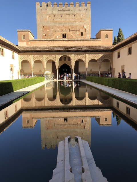       Palace with a reflective pool and people taking photos.
  