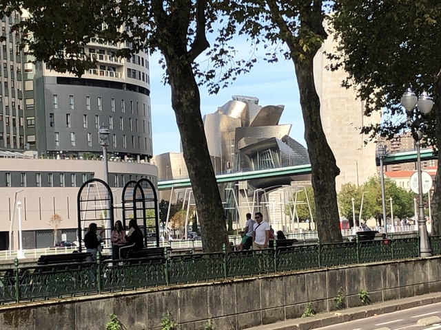       Modern building with unique architecture by a river.
  