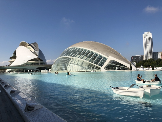       Modern buildings and a curved bridge over a water area.
  