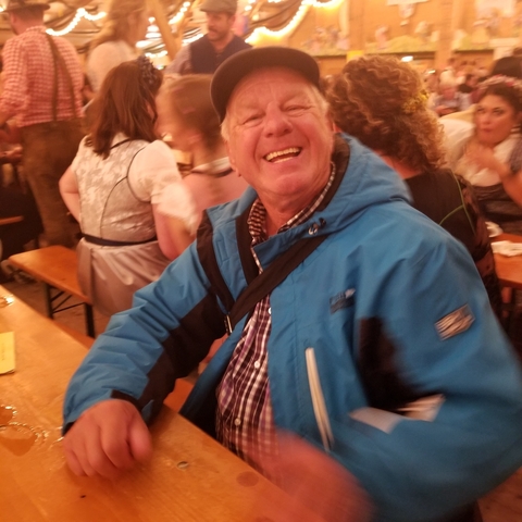 Man in a blue jacket smiling at a festival.