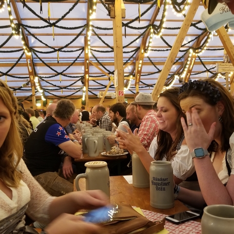 People sitting at a table with large beer mugs at a festival.