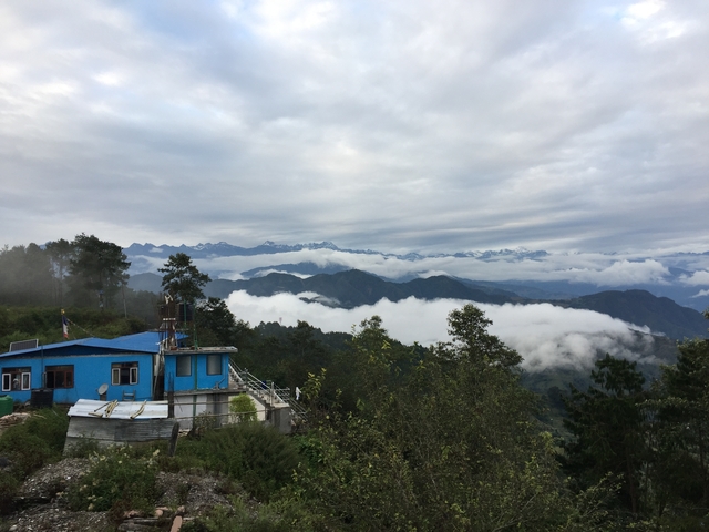       Mountain range with a blue building in the foreground.
  