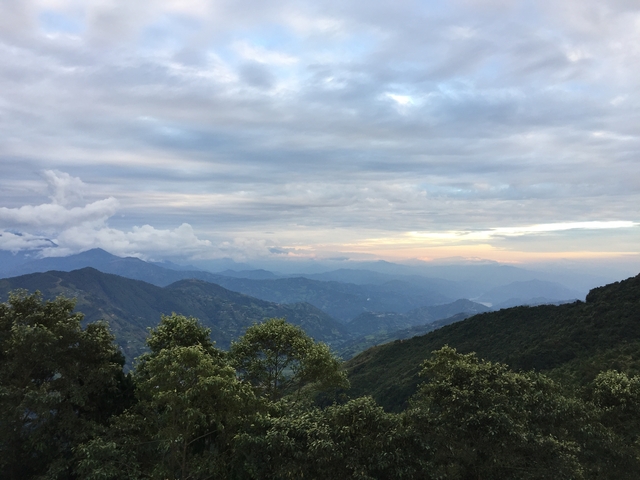       Expansive view of mountains and valleys with a cloudy sky.
  