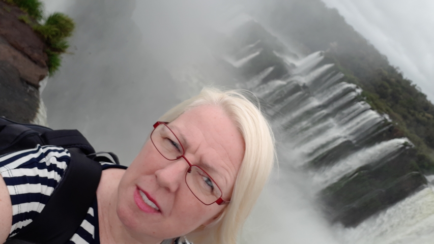 Individual posing in front of waterfalls.