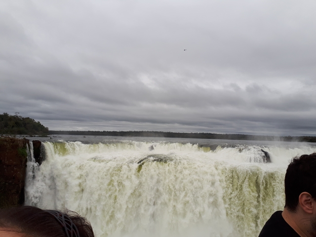 Expansive view of a waterfall with cloudy sky.