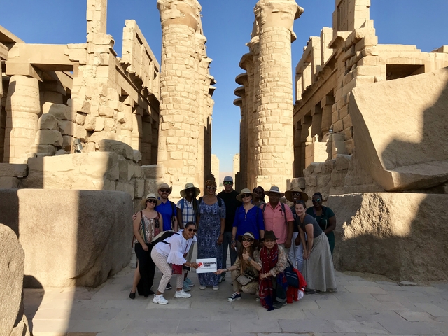       Group of people posing in front of ancient ruins with tall stone columns.
  