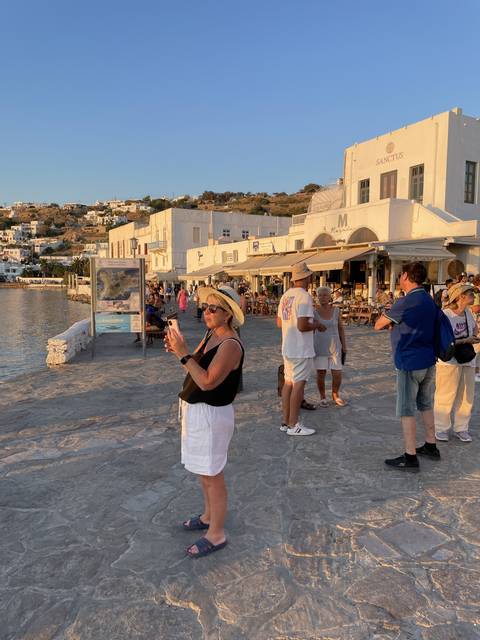       Busy street in a coastal town with tourists and shops.
  