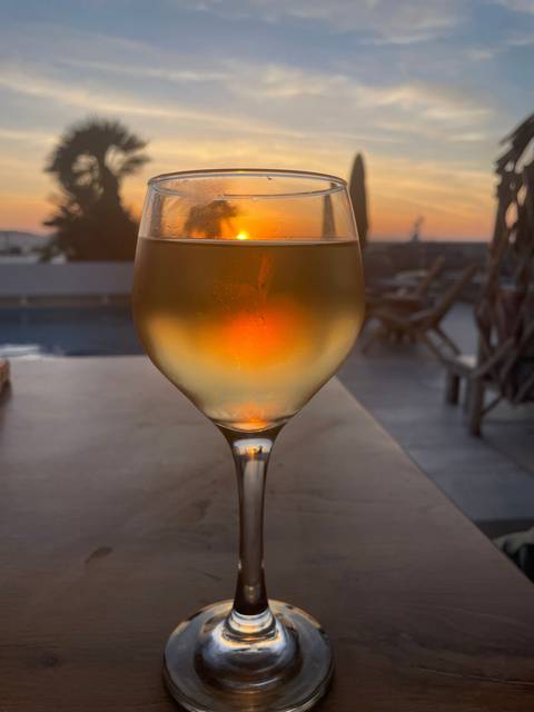 A glass of wine with a sunset background.