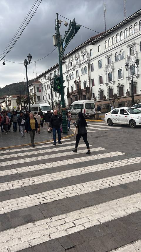       People crossing a street in a city with historic architecture.
  