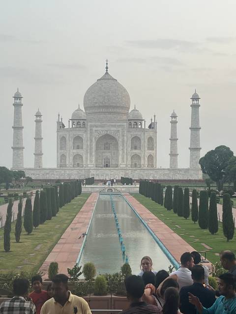       Visitors gathering in front of the Taj Mahal with reflecting pool.
  