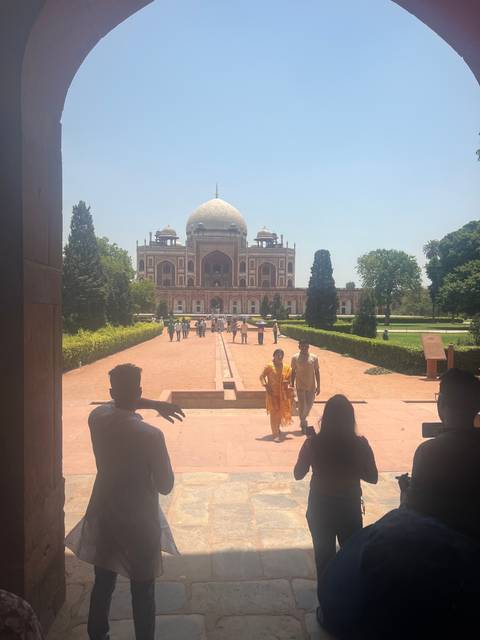       Visitors at an expansive garden with a historic building.
  