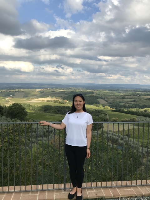 Woman posing in front of a scenic vineyard landscape.