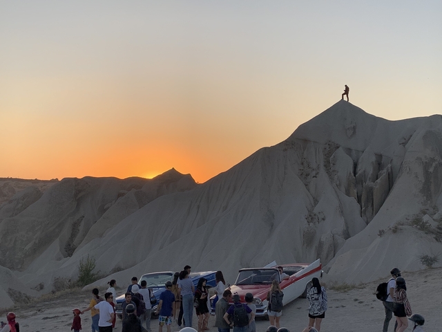 Person standing on a rocky cliff at sunset.