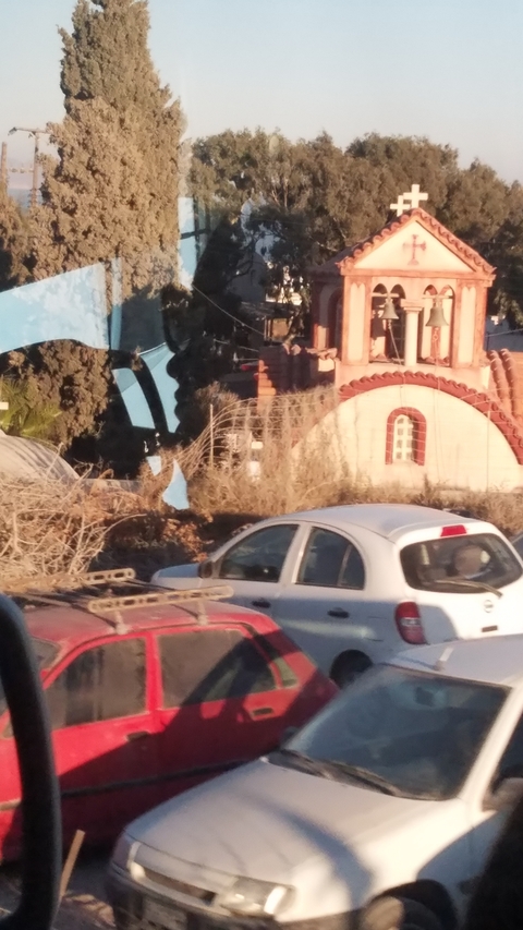       Buildings and a parked car with a small structure in the background.
  