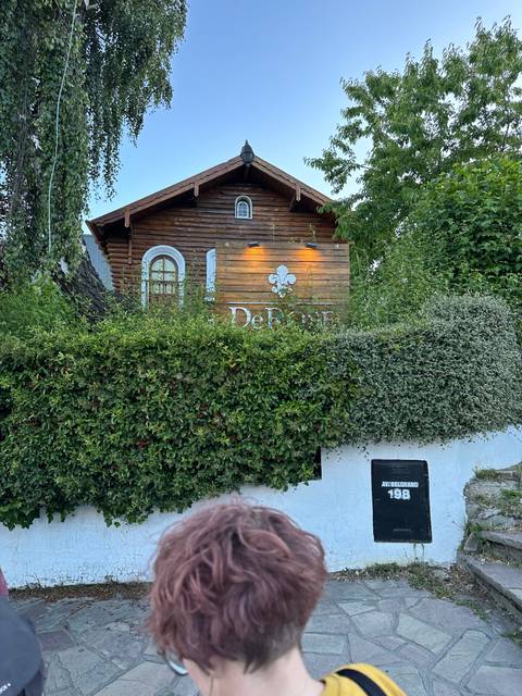       Small wooden house with a sign partially obscured.
  