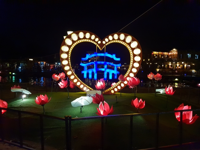 Illuminated heart and lotus decorations at night.