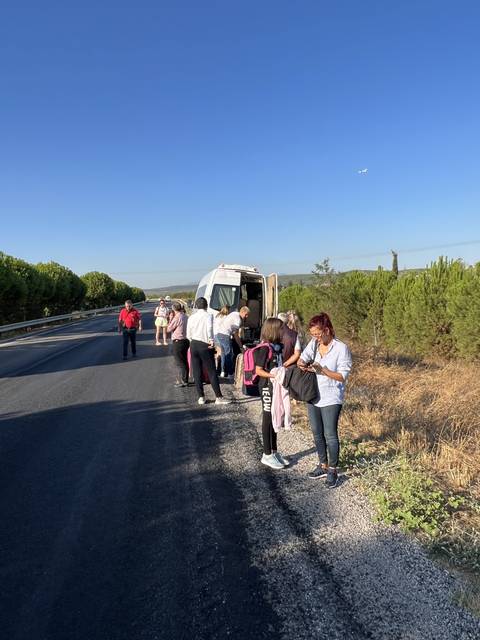       Group of people beside a parked van on a road.
  