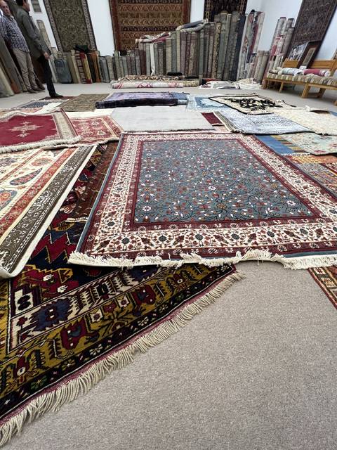       A variety of colorful rugs displayed in a shop.
  
