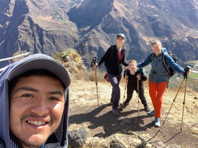 Group selfie on a hiking trail with rugged landscape.