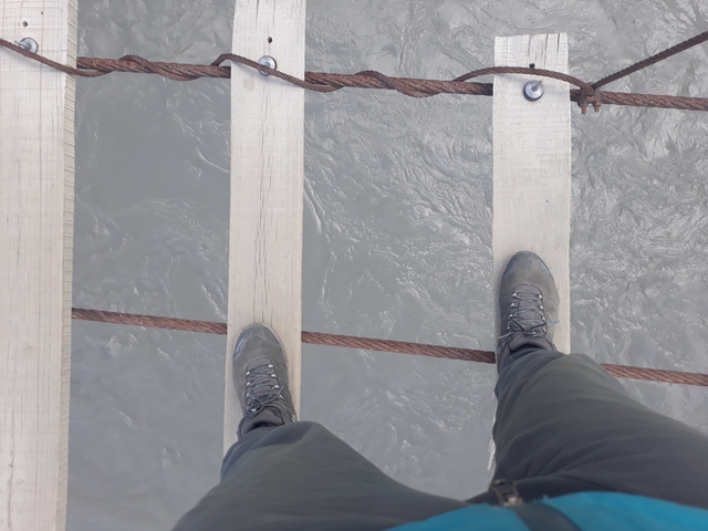 A person walking on a narrow suspension bridge.