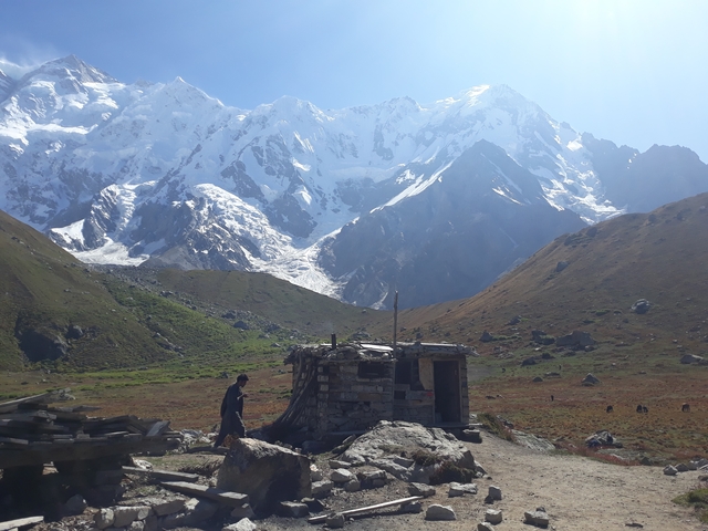       A small stone hut in a mountain valley.
  