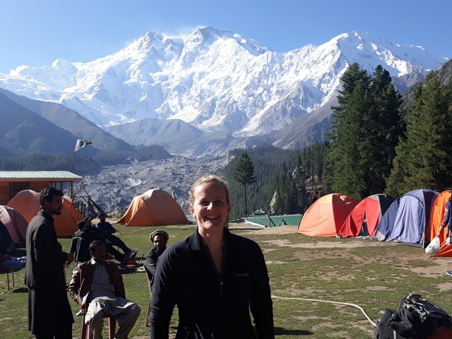 A person standing in front of a campsite with mountains in the background.