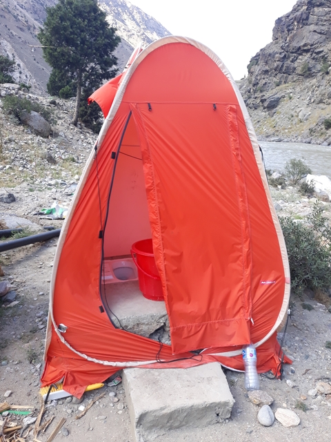       A portable toilet set up beside a river.
  
