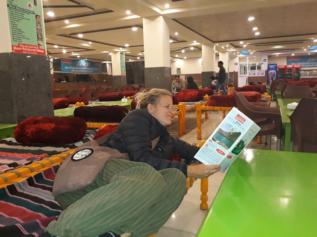 A woman reading a menu in a restaurant with traditional seating.