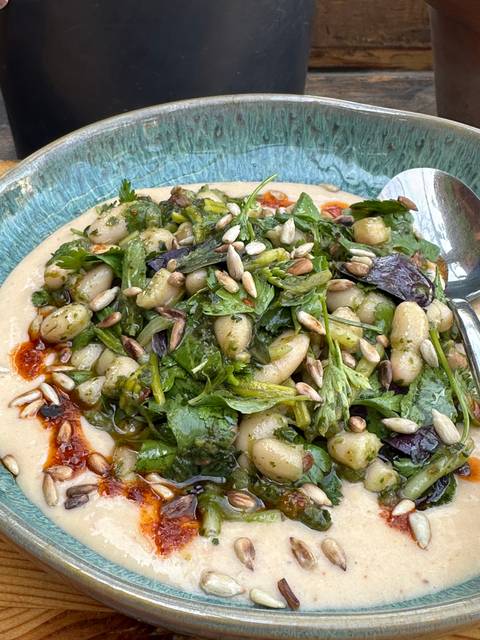       Salad with greens, herbs, and a mustard dressing on a plate.
  