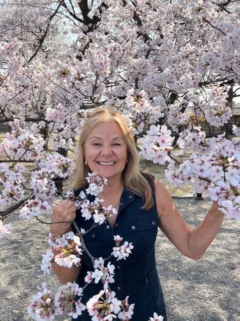 Woman posing with cherry blossoms in daylight.
