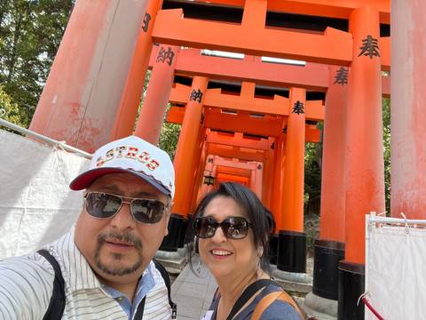       Two people posing under red torii gates.
  