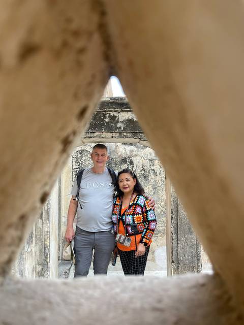       Couple posing behind a stone archway.
  