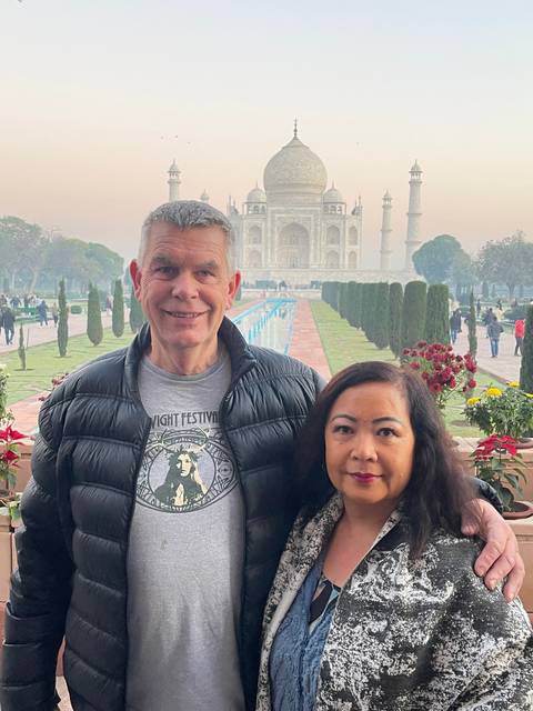       Couple posing with the Taj Mahal in the background.
  