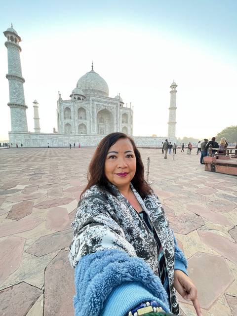       Woman taking a selfie with the Taj Mahal.
  