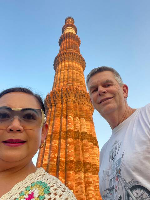       Two people posing with a tall brick tower.
  