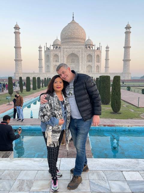       Couple posing in front of the Taj Mahal.
  