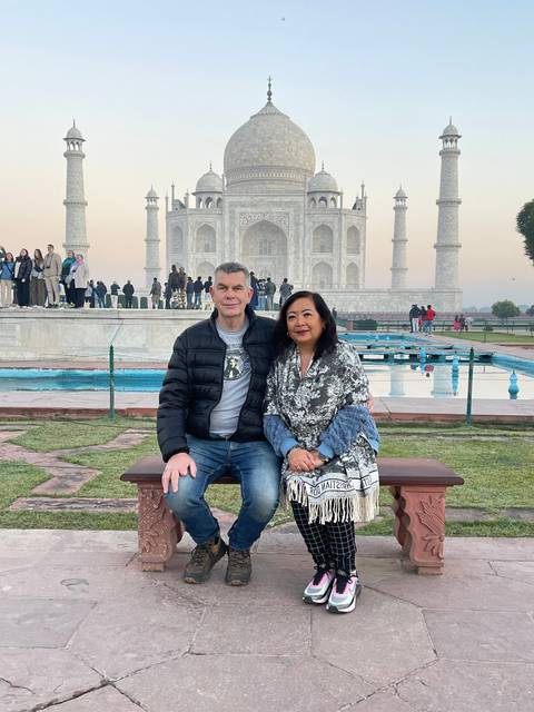       Couple sitting in front of the Taj Mahal.
  