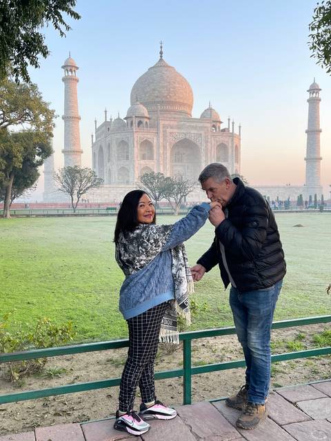       Couple posing with Taj Mahal in the background.
  