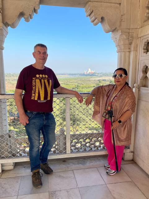       Couple standing on a balcony with a distant view.
  